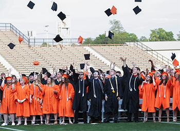 A group of high school graduates throwing their hats in the air.
