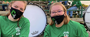 Two young women with college band uniforms on, smiling for the picture.