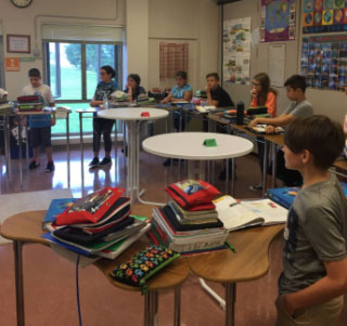 A group of students standing behind desks in a semi-circle