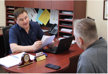 Two teachers discussing papers at a desk