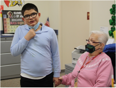 An older woman holding the hand of a young student at school