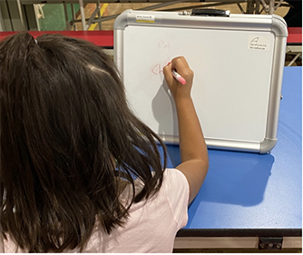 A kid writing on a small white board.