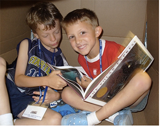 Two kinds reading a book together on the floor.