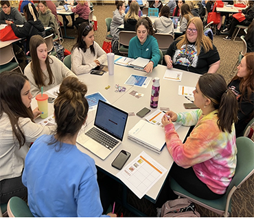 Young adults sitting around a table with school supplies