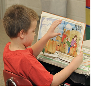 A kid holding up a good and reading