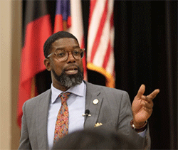 A man in a suit and tie talking to an audience