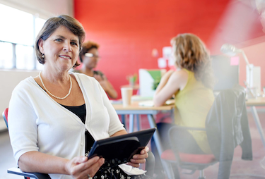 Female administrator in a chair with a clipboard smiling