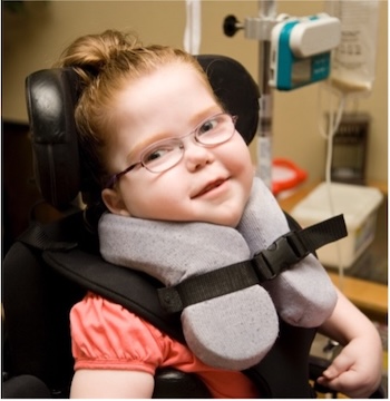 Girl smiling in a wheelchair with a neck brace and glasses