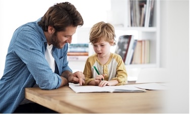 Man and a young boy working out of a workbook at a table together