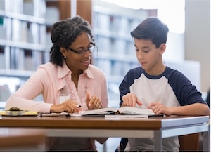 Teacher and a student working at a desk in the library together