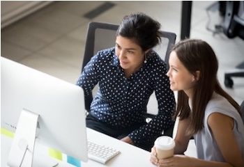 Two women working together at desktop computer